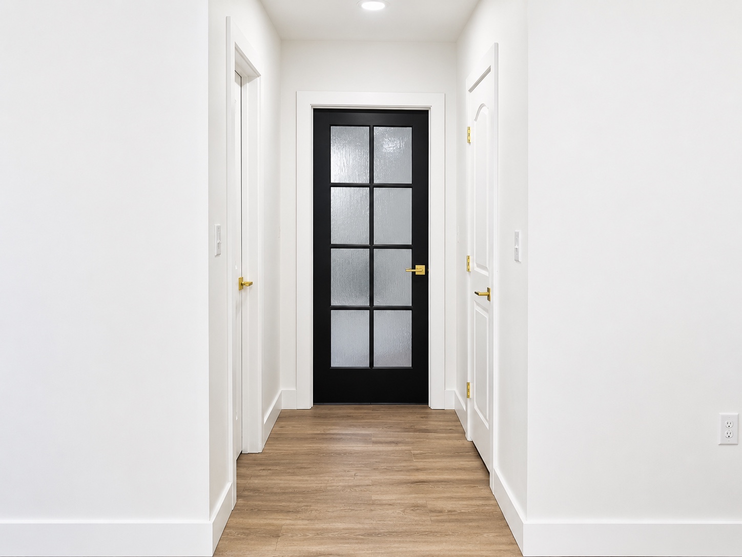 Interior finish details with black door, white trim, and wood flooring by Elite Construction and Design